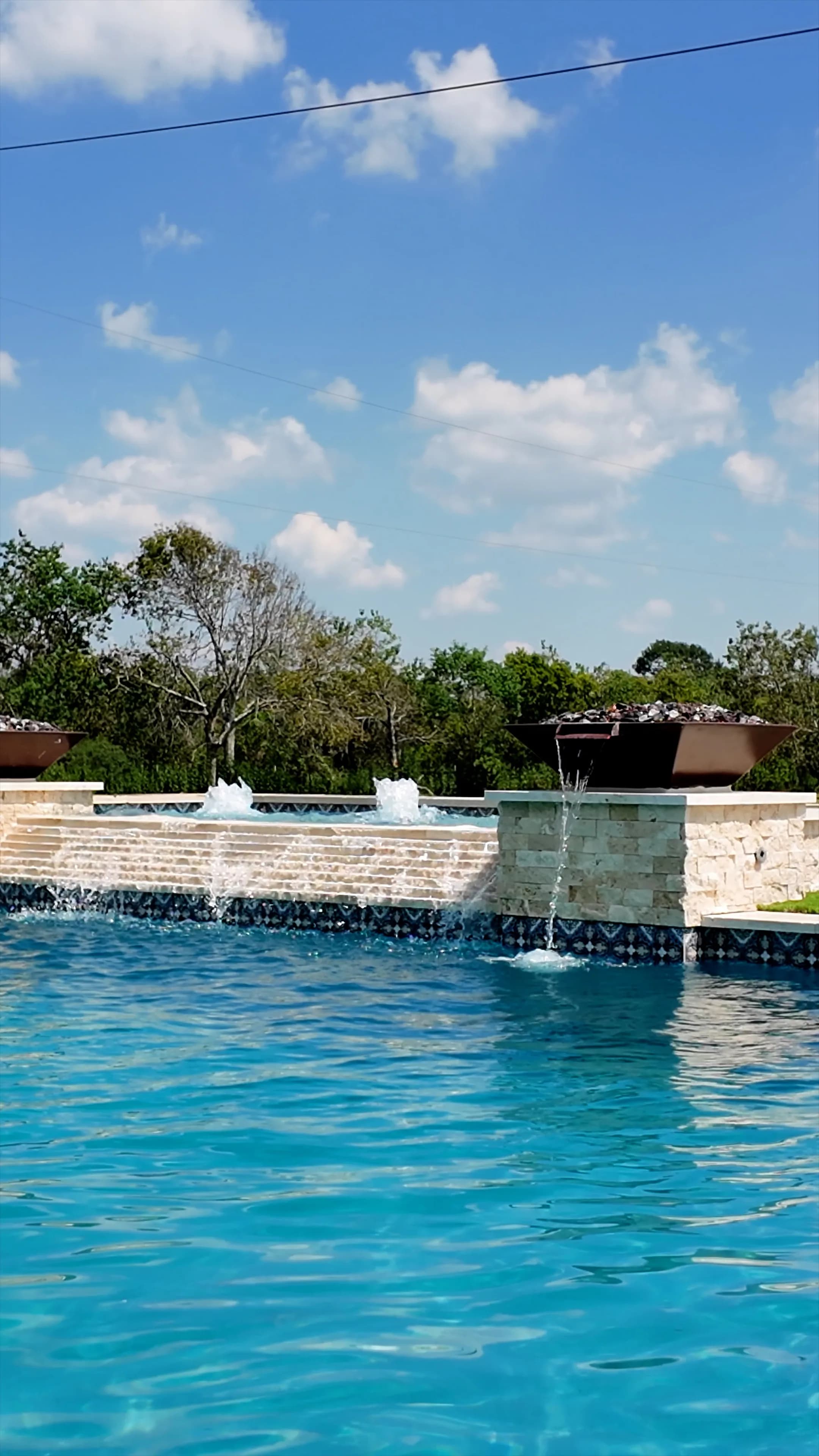 Travertine spillway cascade and a copper bowl's water spout feeding the main pool