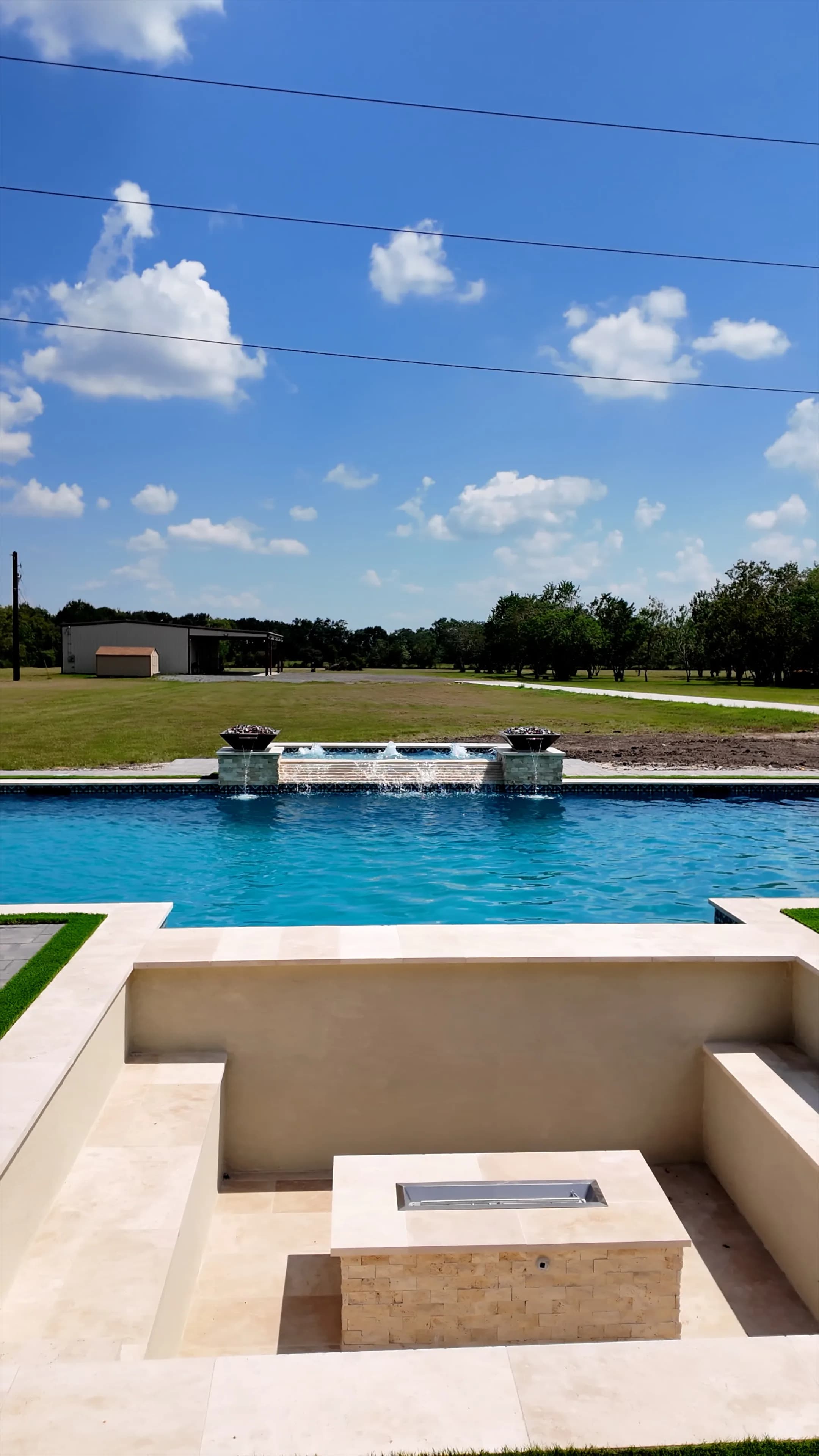 Sunken fire pit seating facing the pool's spillway wall and twin copper fire bowls