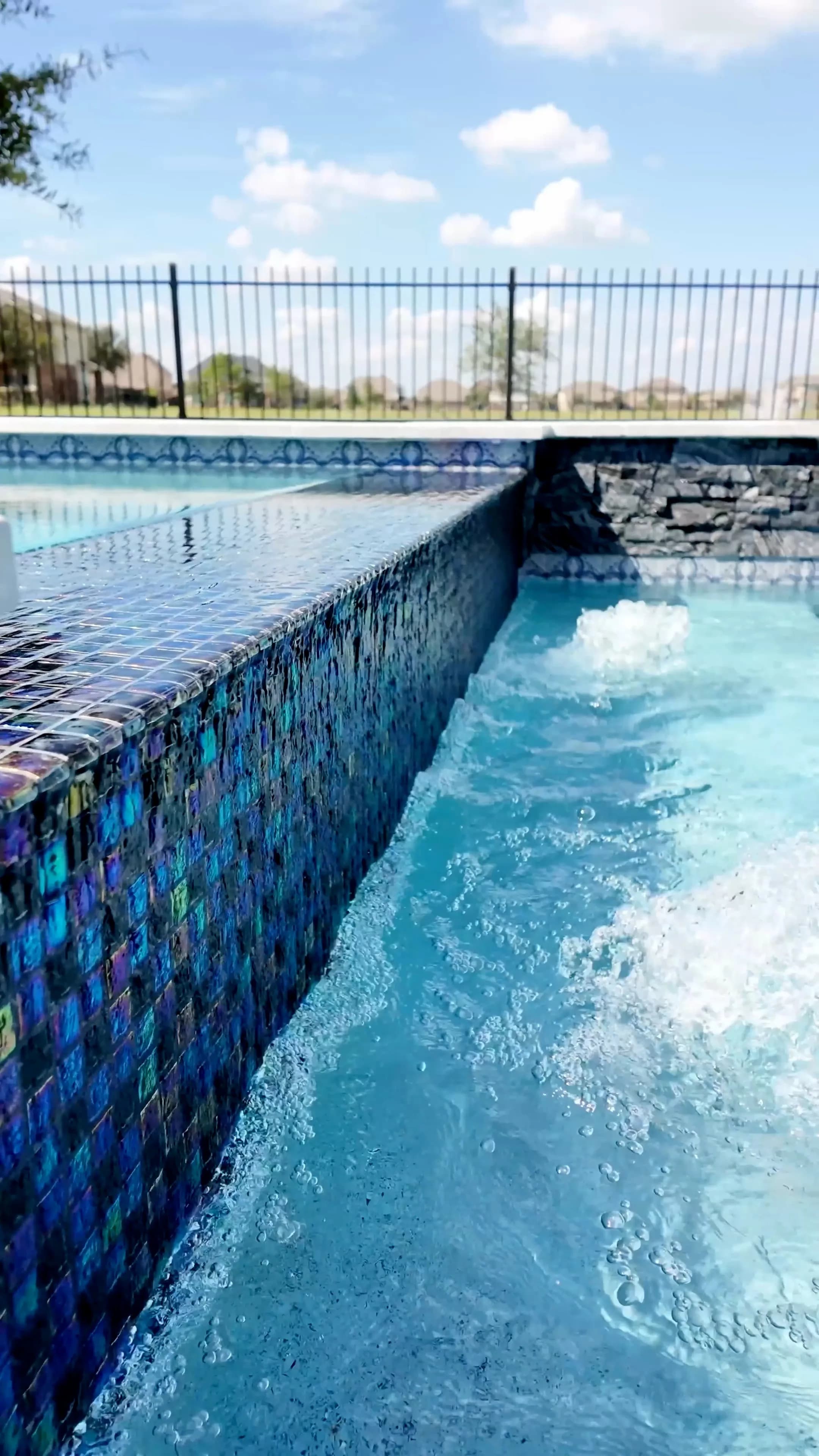 Close-up of the spa's iridescent blue glass tile wall with bubblers breaking the surface