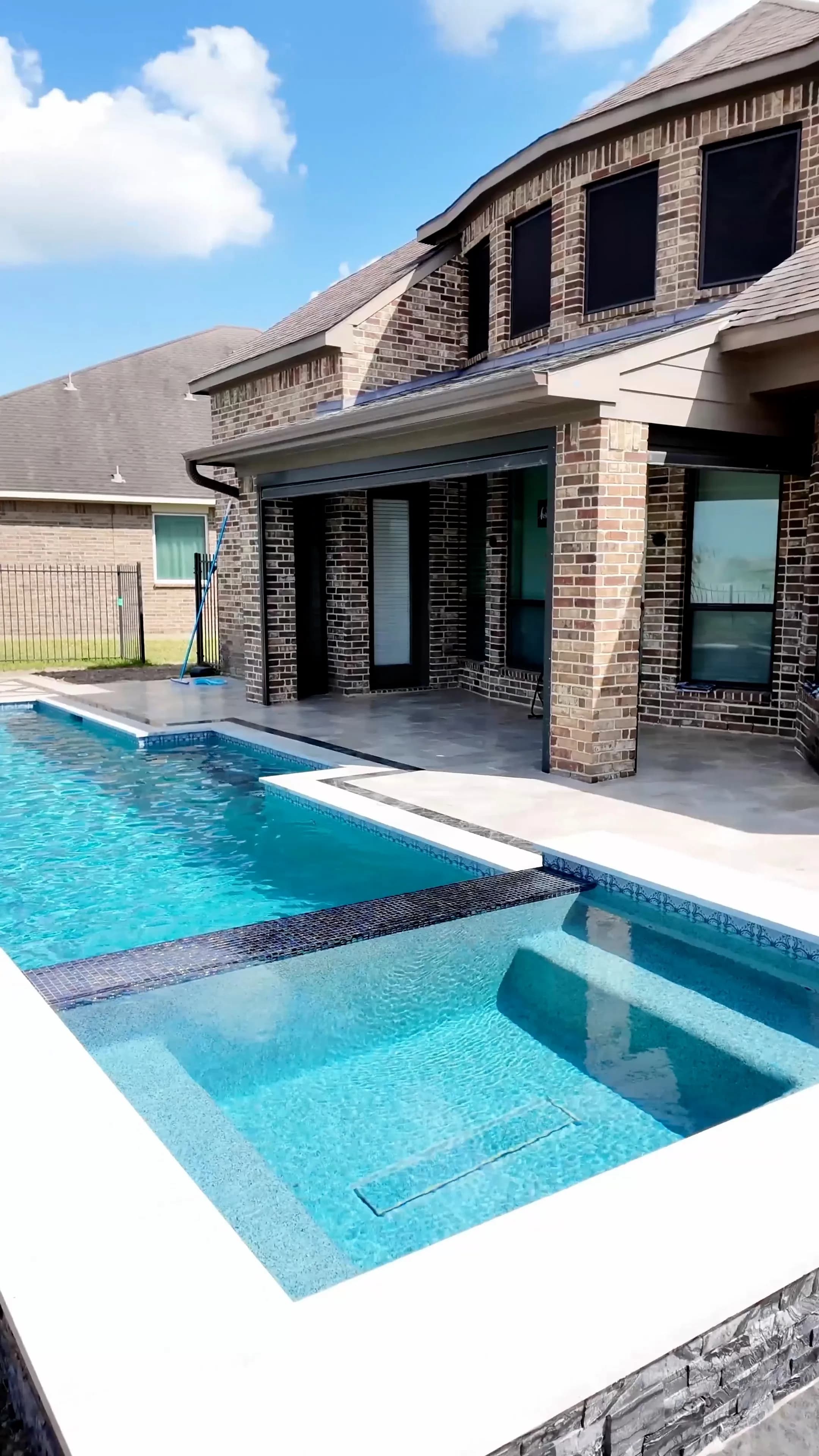The spa and pool meeting the home's covered patio and brick columns