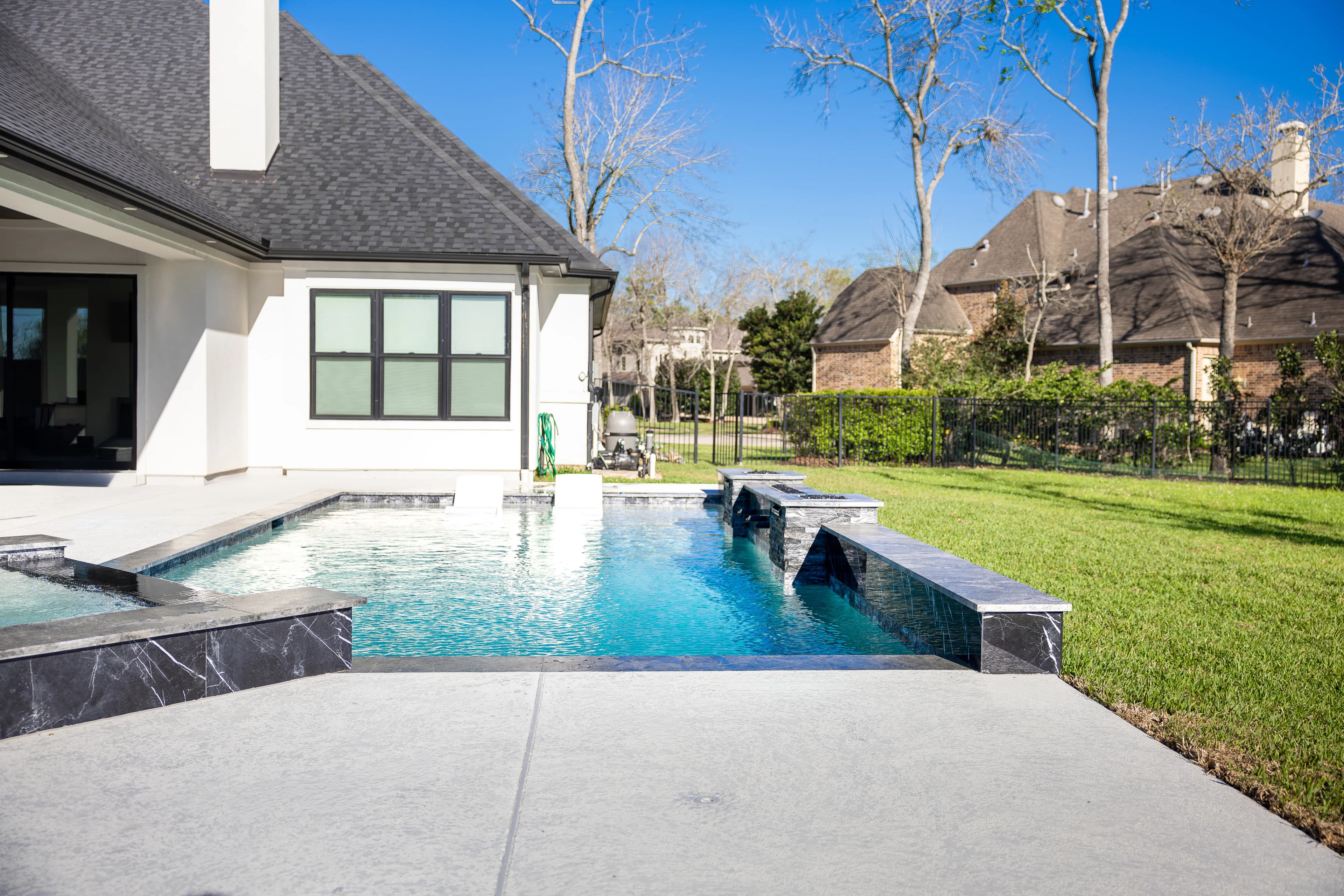 View across the pool and glass-tile spa toward the home's covered patio in Missouri City, TX