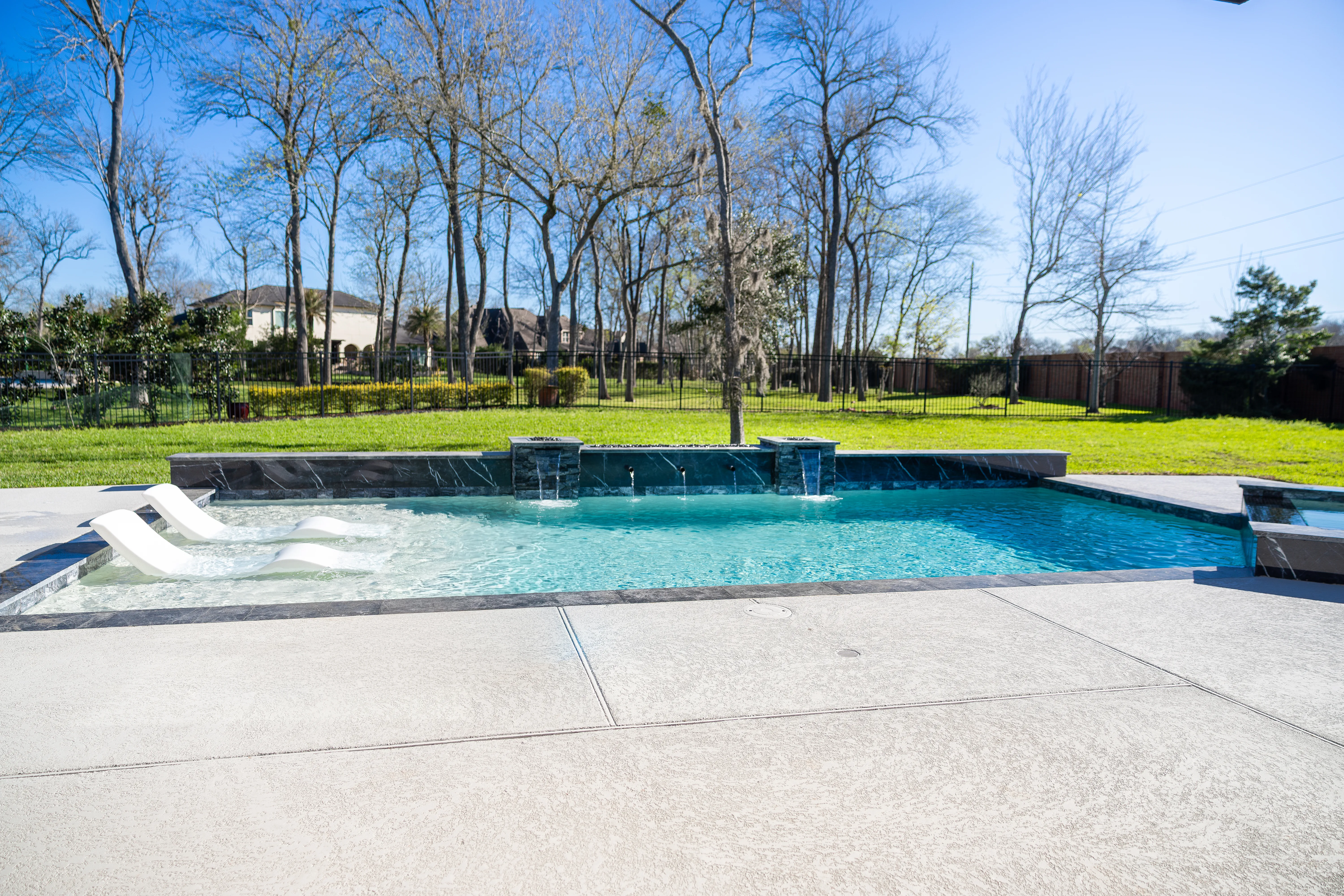 Geometric gunite pool with dual fire pits and sheer-descent waterfalls in Missouri City, TX